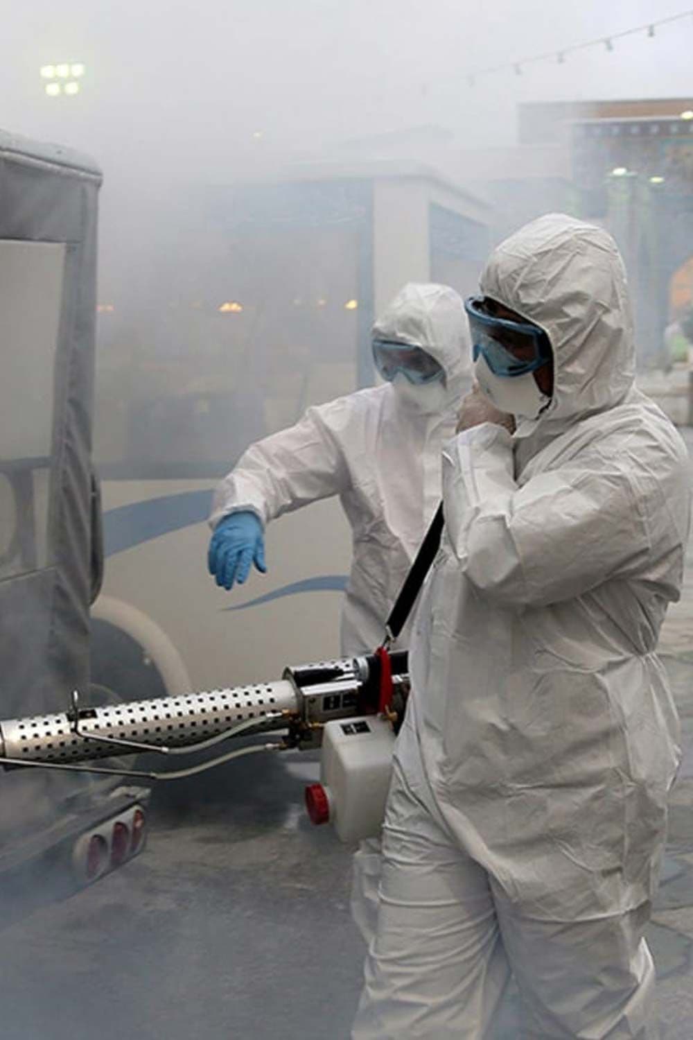 Technicians in protective gear using outdoor fogging equipment